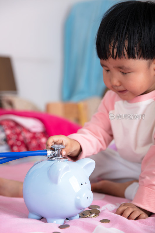 小女孩正在为小猪存钱罐听诊概念图片