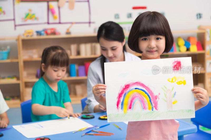 幼儿园女老师和儿童展示绘画作品