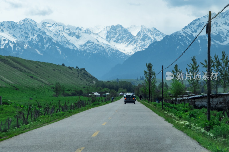 新疆伊犁恰西草原上通往雪山的公路