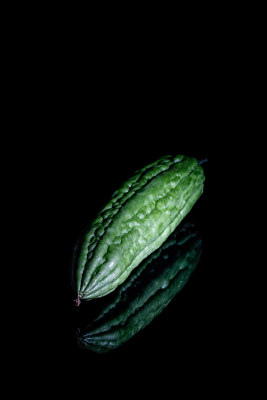 黑色背景上的新鲜绿色蔬菜瓜果苦瓜