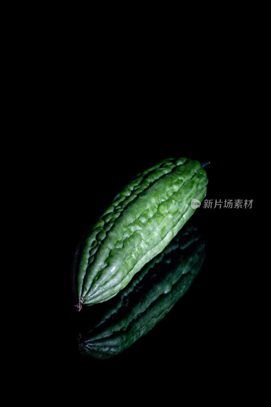 黑色背景上的新鲜绿色蔬菜瓜果苦瓜