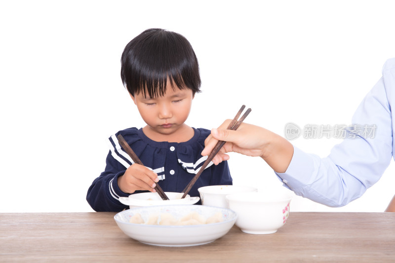 餐桌前妈妈在帮助自己的女儿吃饺子