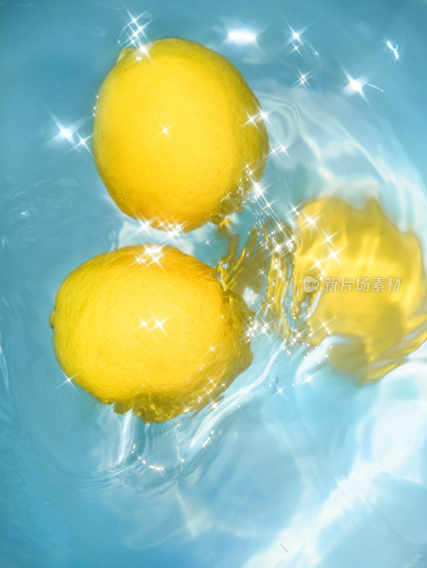 蓝色的水中漂浮着新鲜的黄色柠檬