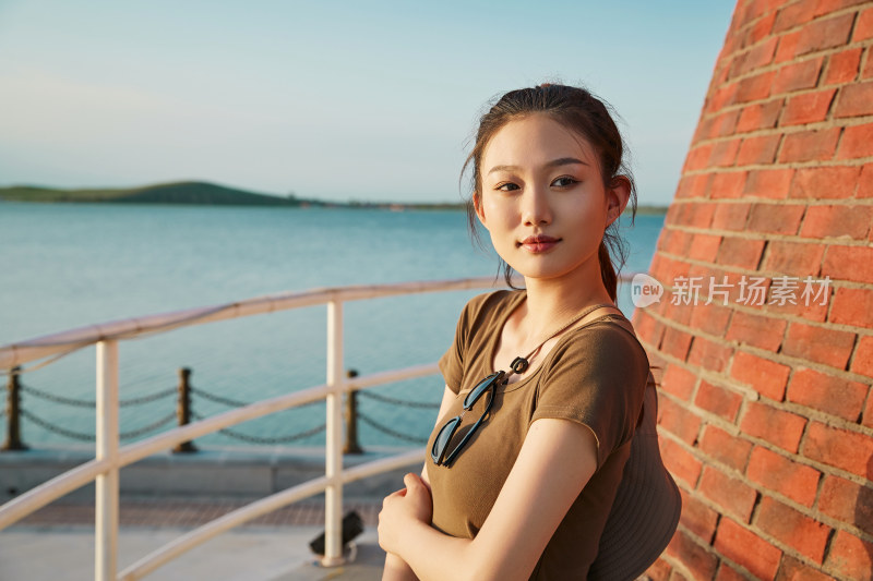 盛夏夕阳晚霞湖边码头灯塔上的少女