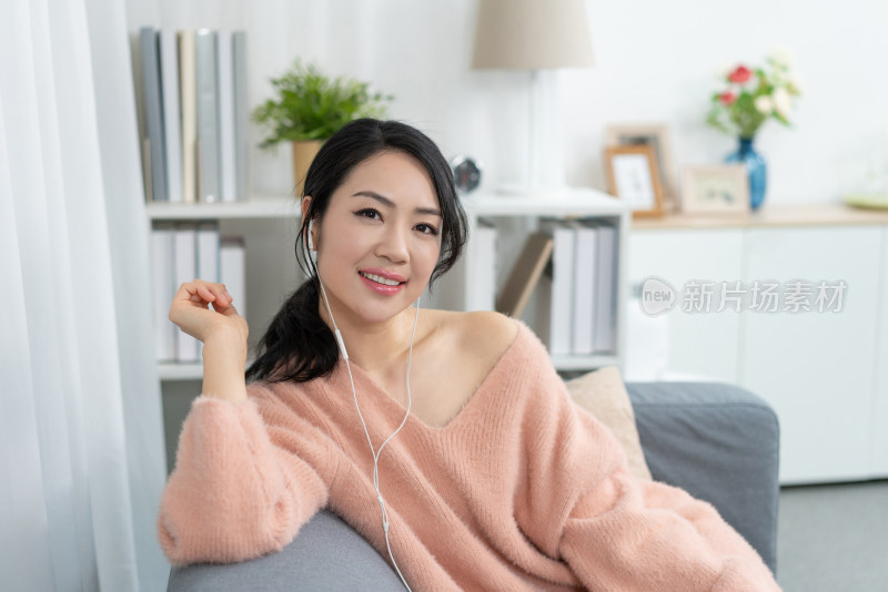 年轻女子坐在沙发上听音乐