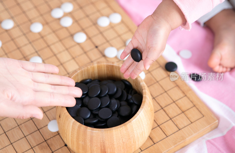 一只小手正把棋子放入棋盒中