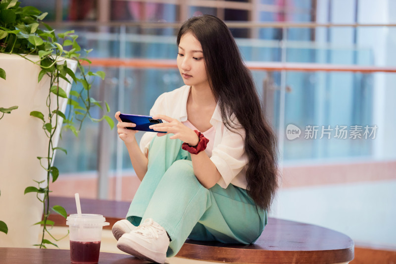 假日在商场休息区用手机自拍的中国少女