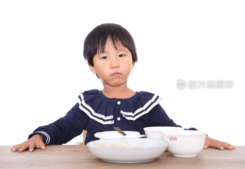 白背景上的餐桌前中国小女孩在吃饭