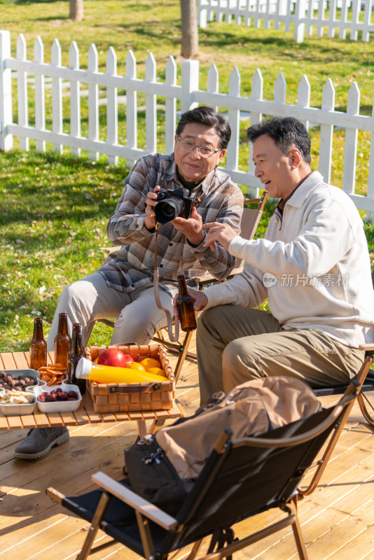 两个老年男人坐在露营地看数码相机