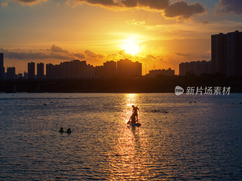 夕阳下玩桨板的人