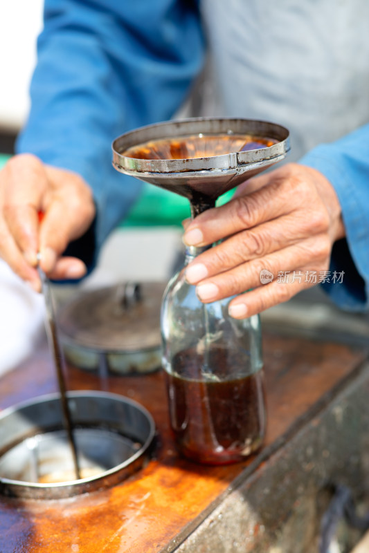 卖香油的小商贩灌香油特写