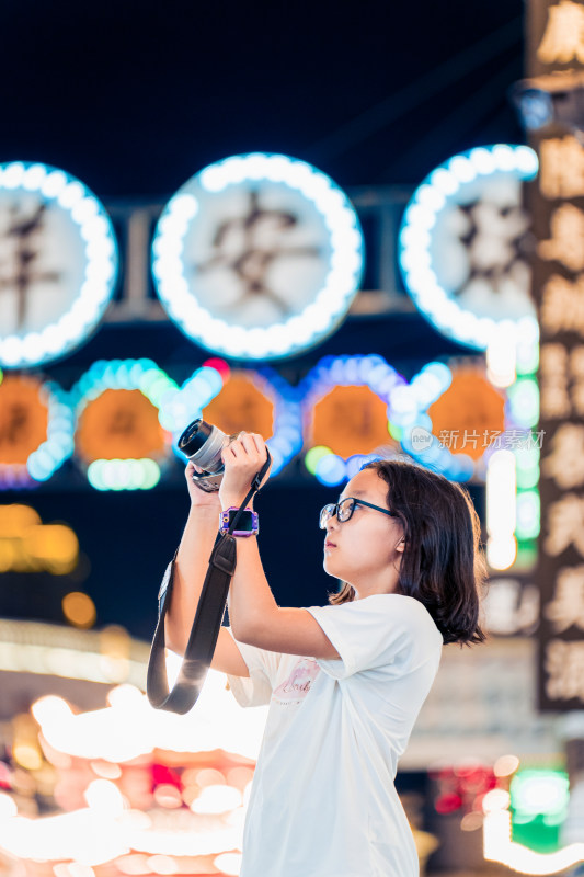 少女夜晚手持相机拍摄灯光夜景