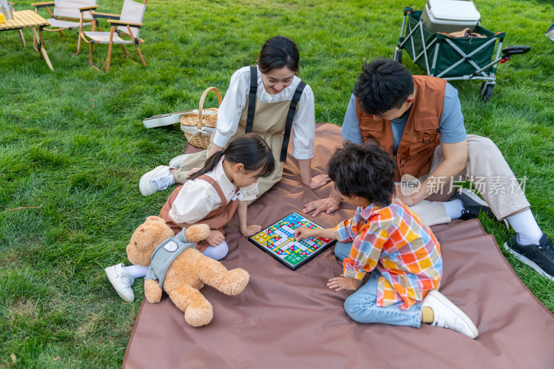 一家四口坐在野餐垫开心玩游戏