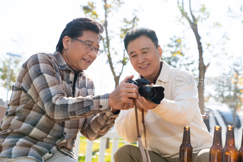 两个老年男人坐在露营地看数码相机