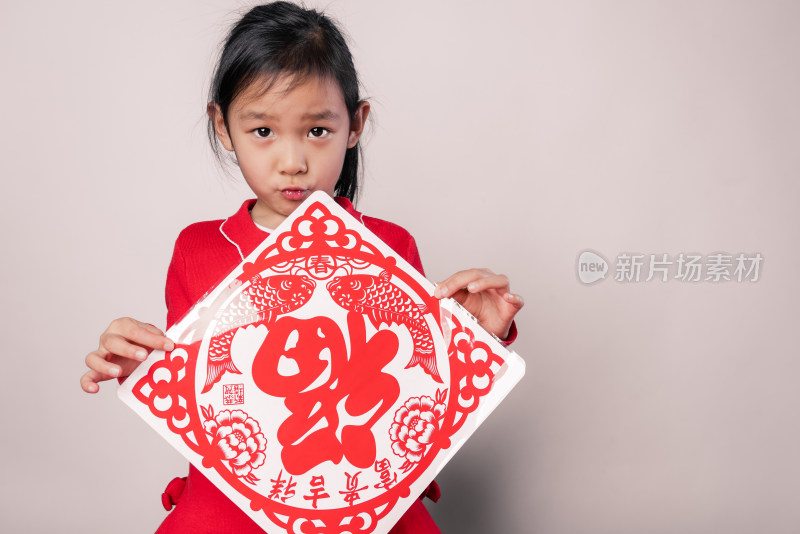 在白色背景前展示剪纸窗花的中国女孩