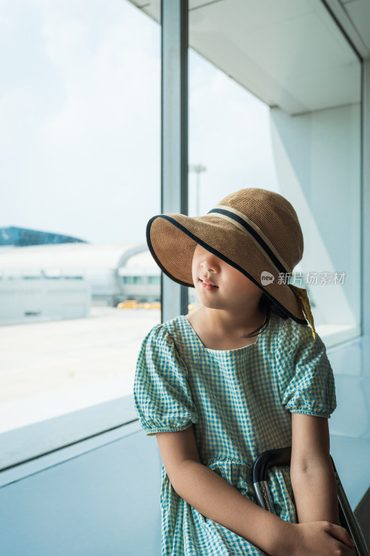 拖行李箱在机场等待登机的中国女孩