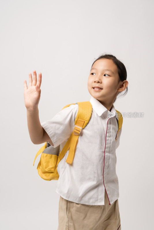 白色背景前穿校服挥手的中国女孩