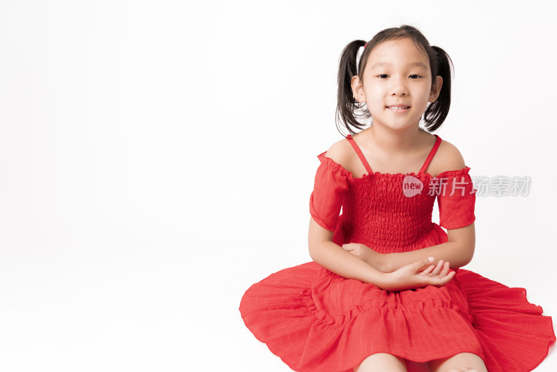 白色背景前穿红色连衣裙坐在地上的女孩