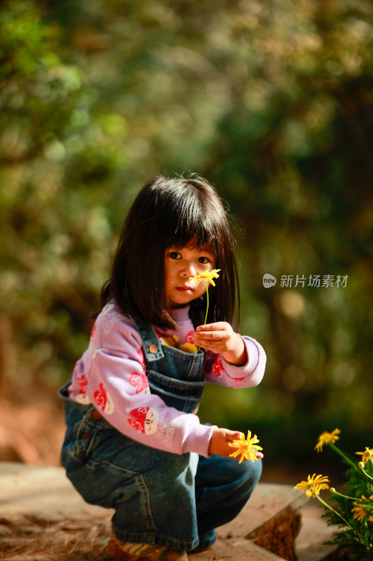 小女孩手持黄色花朵户外可爱模样