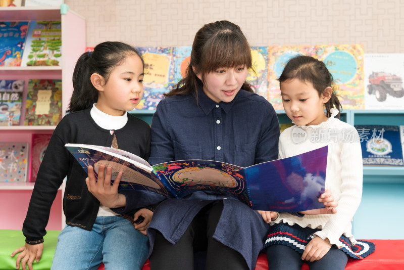年轻的母亲陪伴两个孩子阅读书籍