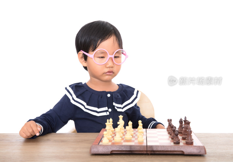 戴着眼镜框的中国小女孩在认真的下国际象棋