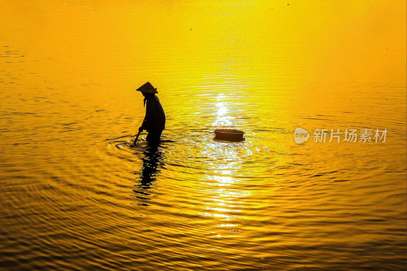 渔夫在被日落余晖照的波光粼粼的湖面捕鱼