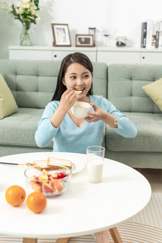 一位年轻女士在家吃早餐喝粥