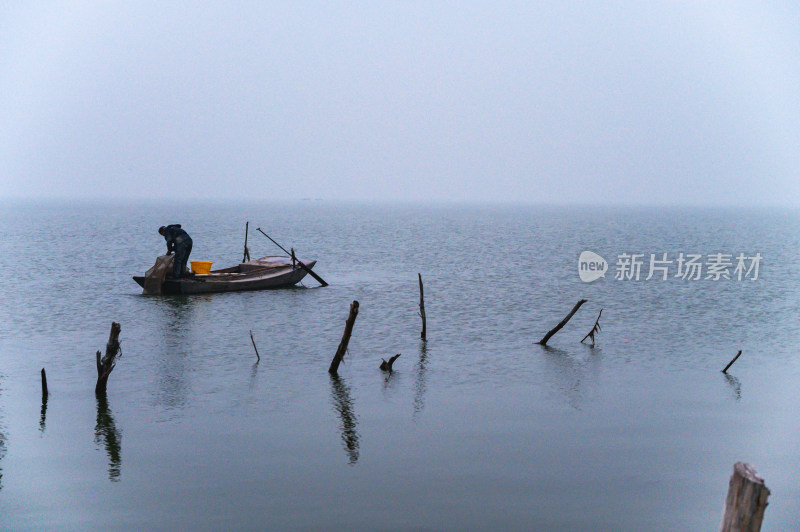 秋天早晨江面雾气与渔船捕鱼人