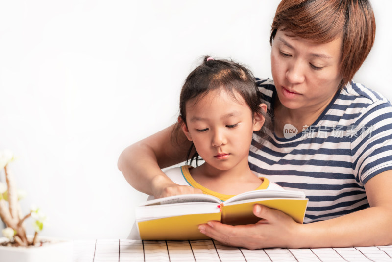 白色背景前年轻的中国籍母女在读书