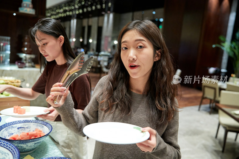 在酒店自助餐厅大吃特吃的亚洲可爱闺蜜少女