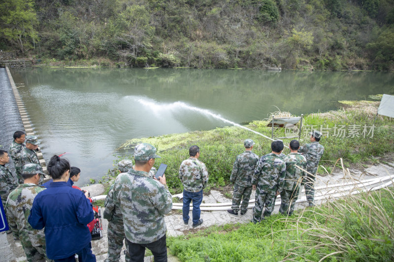 民兵在河边演练抽水泵使用
