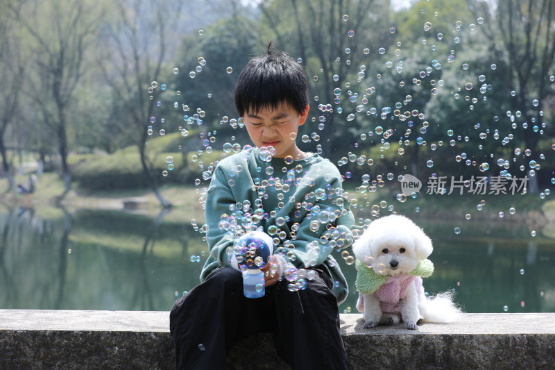 可爱的男孩和她的狗坐在湖边