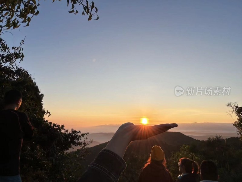 手托夕阳的户外登山赏景画面