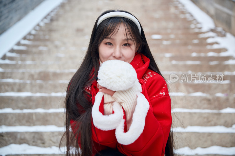 雪后在老城古巷穿着喜庆服饰的亚洲少女