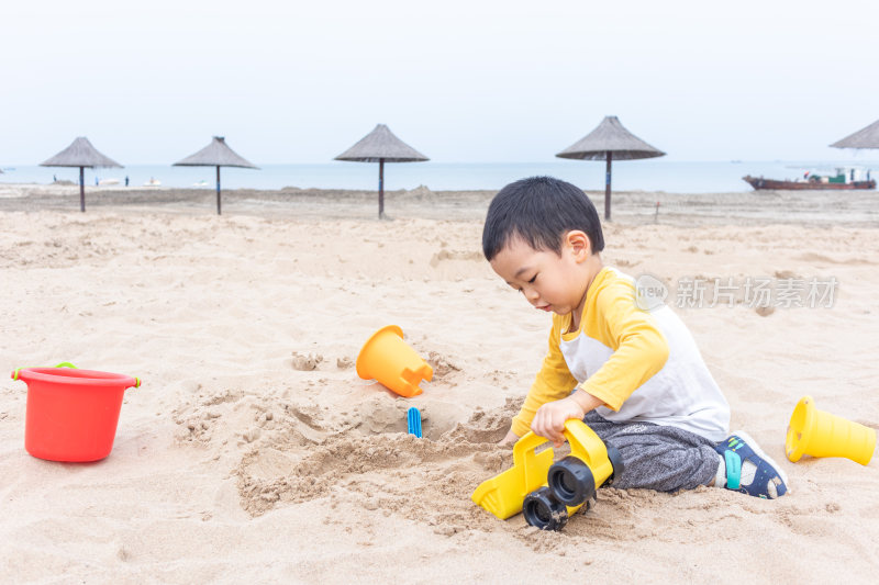 快乐的小男在海边玩沙子