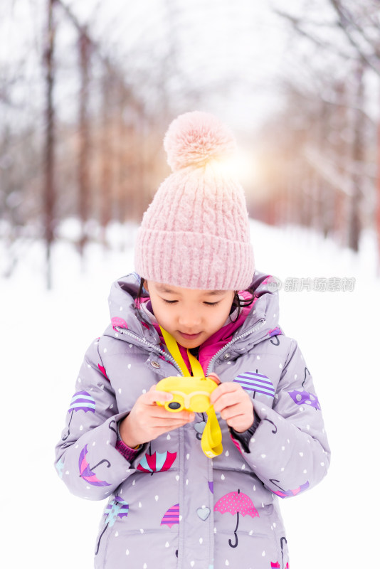在雪地中专注玩儿童照相机女孩