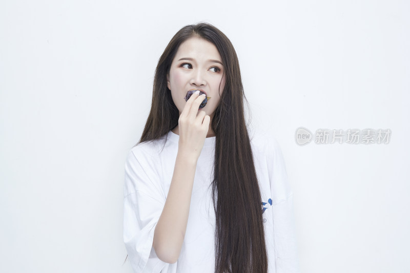 吃西梅的身穿白色长T血衬衫的长发少女人像