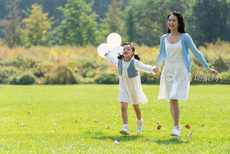 妈妈和女儿拿着气球在草地上奔跑