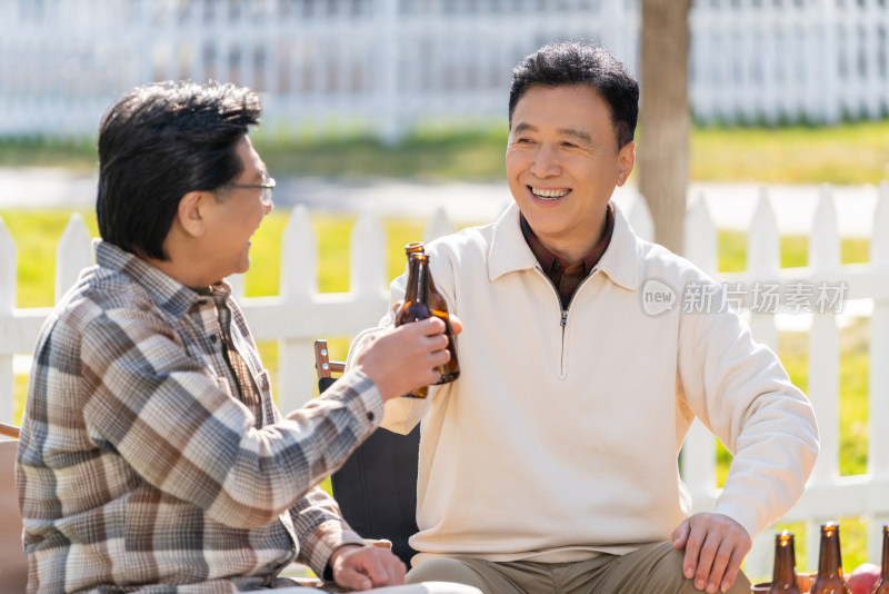 两个老年男人坐在露营地喝啤酒