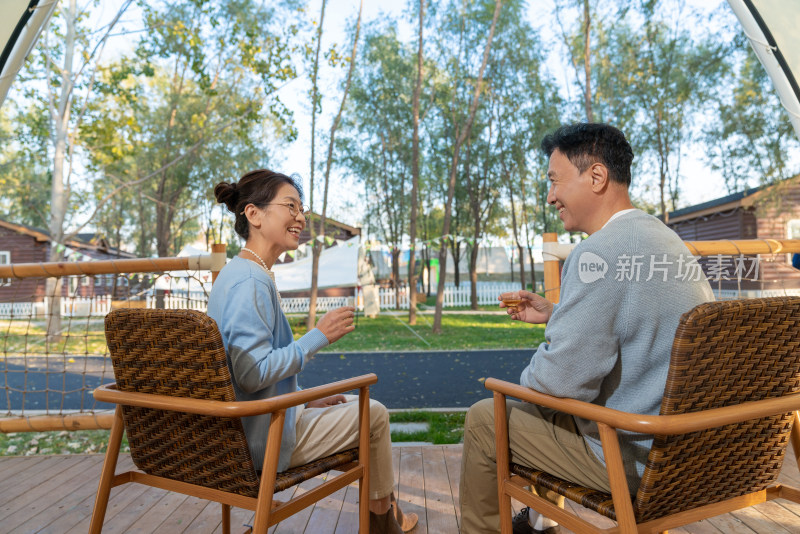 老年夫妻在露营地坐着摇椅喝茶聊天