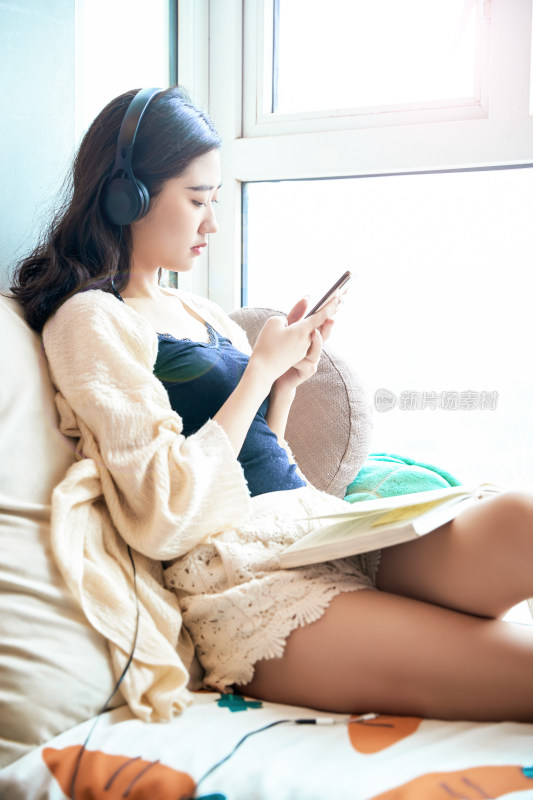 躺在舒适的飘窗上听音乐看书玩手机的女孩