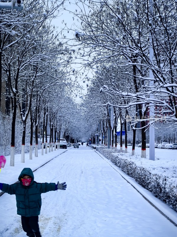 雪中街道上孩子张开双臂奔跑嬉戏