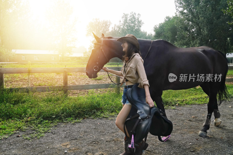 马场内时尚活力的青年女人牵着马