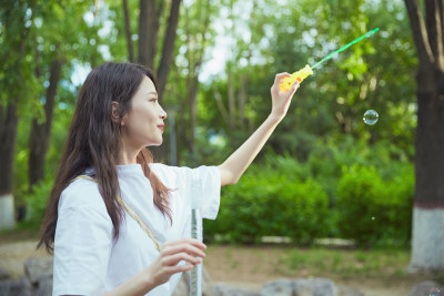 户外公园里玩吹泡泡的可爱亚洲少女