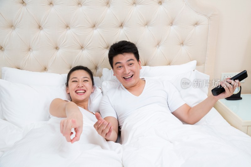 夫妻躺在床上用遥控器