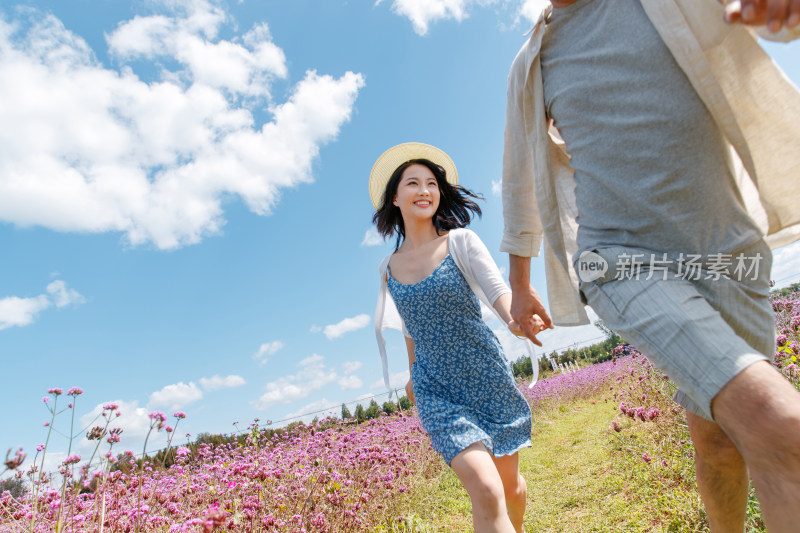 青年夫妇手牵手在花海里奔跑