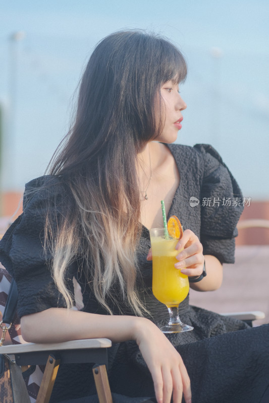 温暖阳光下在海边喝饮料的温柔女子肖像