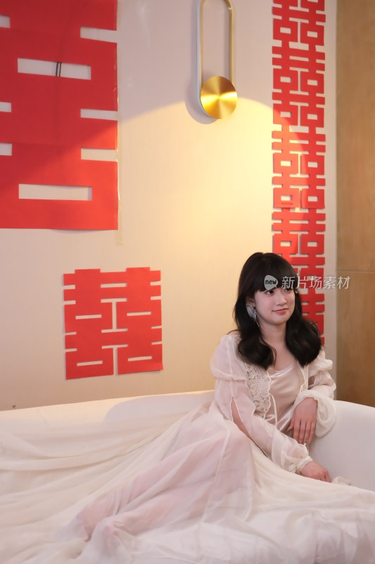 身着纱裙女子坐于喜字背景前