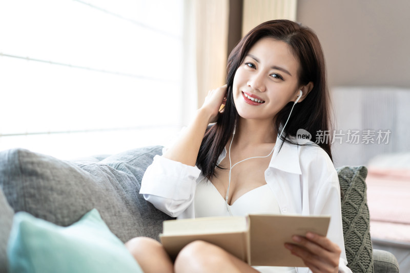 年轻女子在沙发上看书听音乐