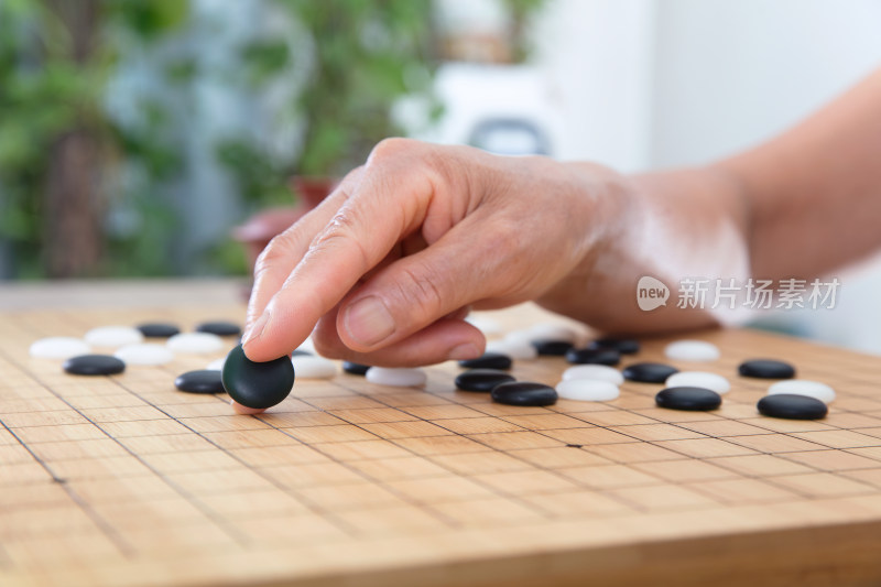 一只手夹着一枚黑色围棋棋子预要落下